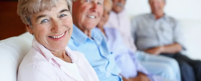 Types of senior care: smiling seniors sit together on a couch in a bright community room