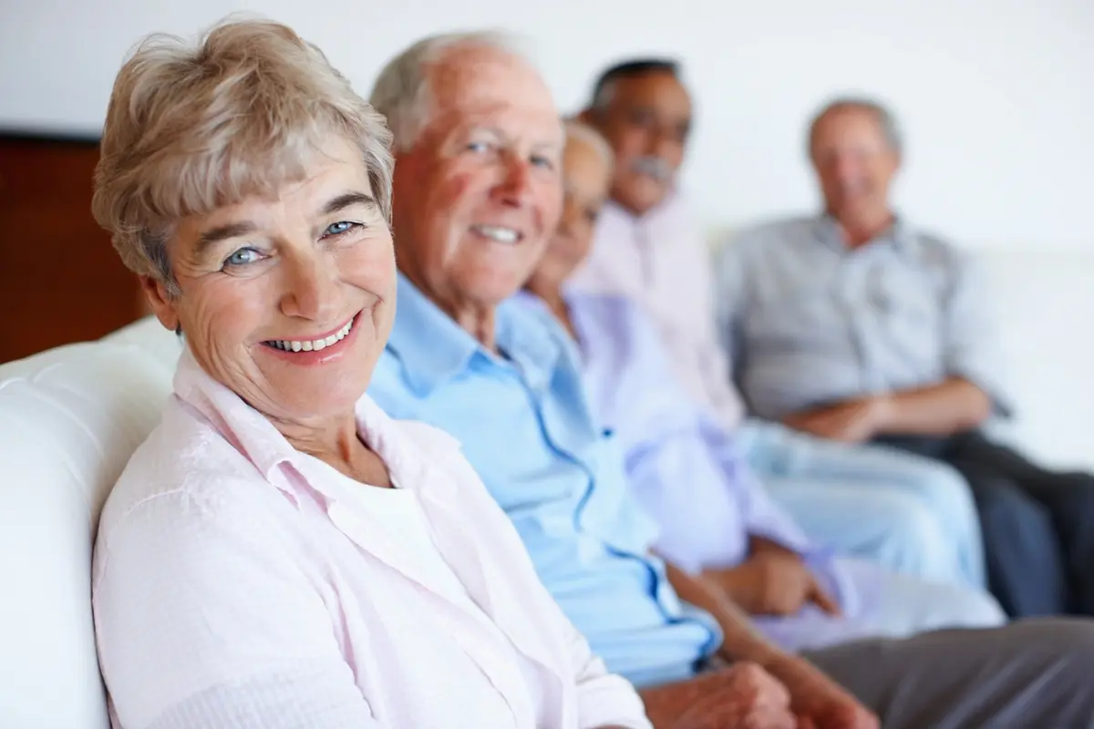 Types of senior care: smiling seniors sit together on a couch in a bright community room
